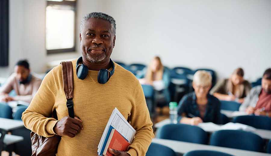 Professional standing in a university learning space with colleagues in the background