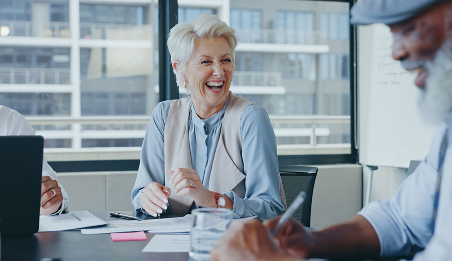 Senior professional laughing during a meeting in a modern university office setting