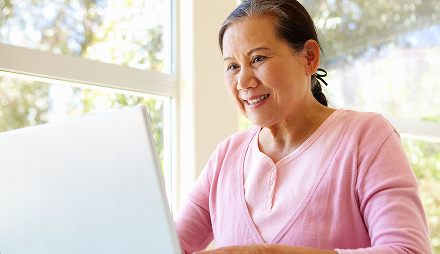 Professional smiling while engaging with a laptop in a bright workspace