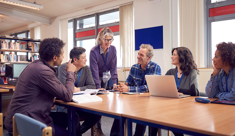Facilitator standing with a group around a table during a collaborative meeting